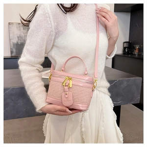 Detailed shot of pink woven box bag with golden zippers and leather brand tag