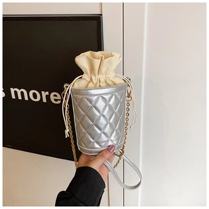 Detailed view of silver quilted bucket bag with beige drawstring lining and chain strap
