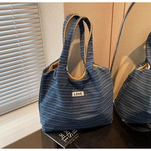 Detail of blue striped canvas tote bag with LOVE patch and high-contrast yellow lining