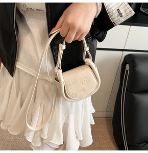 Detailed close-up of cream crossbody bag featuring embossed bear and donut patterns
