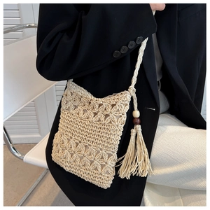 Detail of bohemian straw woven bag with hollow floral pattern and wooden bead tassels