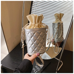 Close-up of a silver quilted bucket bag with a drawstring closure and gold chain strap