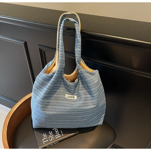 Detail of blue striped canvas tote bag showing LOVE label and magnetic snap closure