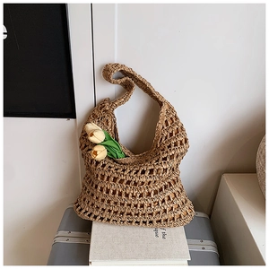 Detail of hollow woven straw tote bag featuring a large mesh pattern and wide strap