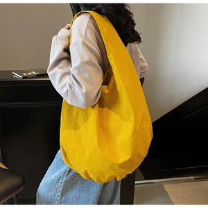 Dettaglio di una grande borsa hobo gialla indossata da una modella in scena casual