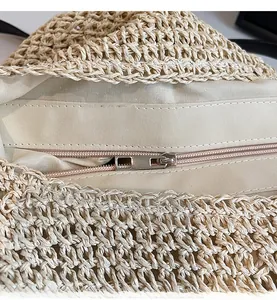 Close-up of a smooth silver zipper closure on a beige woven straw beach shoulder bag