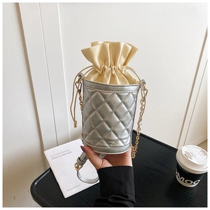 Detail of silver quilted bucket bag with beige drawstring closure and gold chain strap