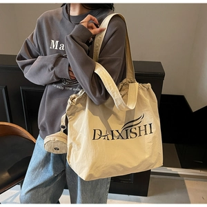 Detailed close-up of large canvas tote bag with side pouch and brand logo text