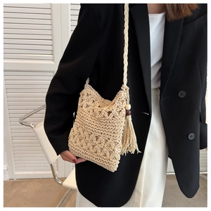 Close-up of beige crochet crossbody bag with hollow floral patterns and fringe with wooden beads