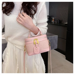 Close-up of pink woven box bag featuring gold hardware and a brand tag detail