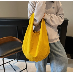 Dettaglio della grande borsa tote gialla in tela morbida con ampia tracolla da spalla