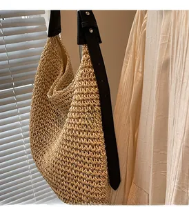 Detail of the woven straw texture and premium dark leather strap on the large tote bag