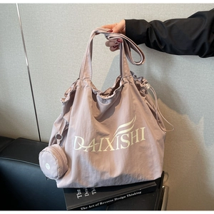 Detail of pink nylon tote bag showing drawstring closure and round coin purse attachment