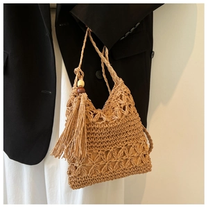 Detailed view of hollow-out straw crossbody bag with tassels and wooden beads
