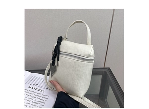 Close-up of white lychee textured crossbody bag with silver zipper and heart pendant