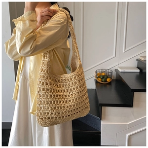 Detail of hollow-out mesh texture and woven straw material on a large beige beach tote bag