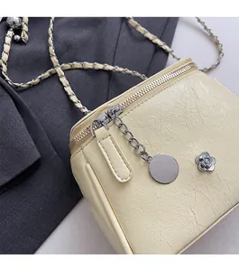 Détail d'un sac bandoulière crème avec fleur argentée et bandoulière en chaîne