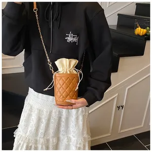 Detail of a brown quilted bucket bag with cream drawstring and delicate chain strap
