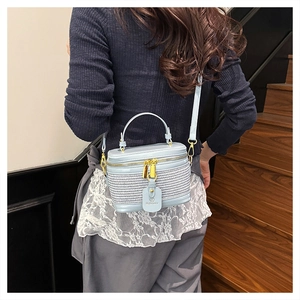 Close-up of light blue leather and woven crossbody box bag with gold double zippers