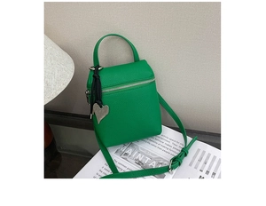 Détail du mini sac carré vert vif à texture litchi et son pendentif décoratif en cœur