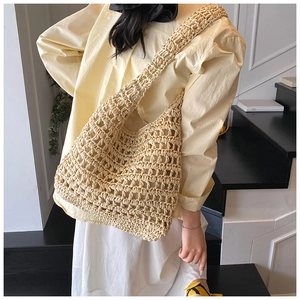 Detail of hollow-out crochet patterns on a beige oversized straw beach shoulder bag