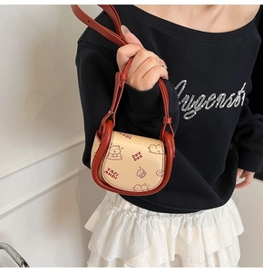 Detail of mini saddle bag with red contrast trim and cute bear print on beige leather