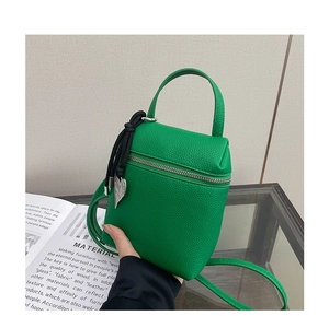 Detail of green litchi texture mini bag featuring a zipper and metal heart charm pendant
