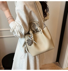 Close-up of apricot bucket bag with lychee texture and heart beaded charm accessory