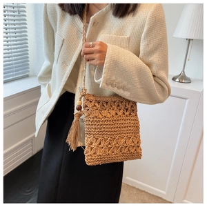 Détail du sac de plage ajouré en paille avec pompons et perles porté en bandoulière