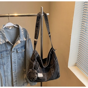 Detail of black washed denim crossbody bag with matching round coin purse and white label