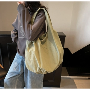 Vista laterale della borsa shopping a pieghe verde oliva portata a spalla per ufficio