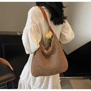 Detailed view of woven straw shoulder bag with leather strap and tulip decoration