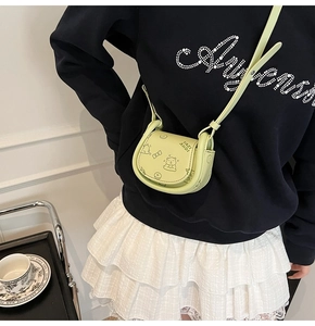 Detail of mint green saddle bag with cartoon bear print worn on the shoulder