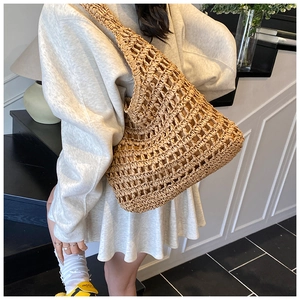 Detail of hollow crochet texture and wide strap on this natural straw tote bag