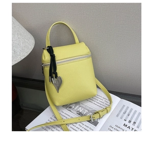 Détail du sac bandoulière jaune texture litchi avec pendentif cœur et zip argenté