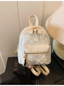 Mini white backpack with floral embroidery and 3D butterfly accents in home setting