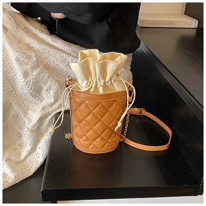 Close-up of a brown quilted leather bucket bag with a beige drawstring canvas inner pocket
