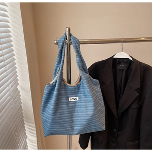 Detail of blue-grey striped fabric tote bag featuring a stitched LOVE patch and roomy interior