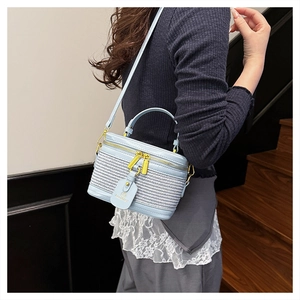 Detail view of light blue cylindrical crossbody bag styled on a female model