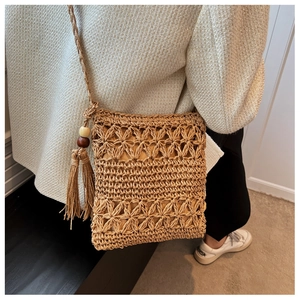 Close-up of hollow straw bag with woven star patterns, tassels, and wood beads