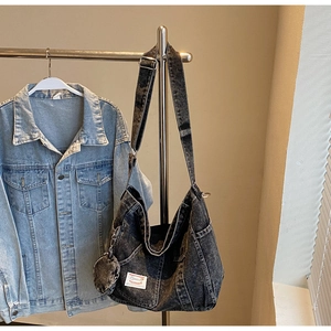 Close-up of a large denim hobo bag with a matching coin purse on a display stand