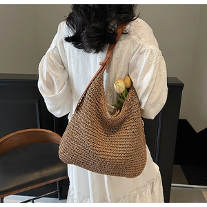 Detail of handwoven straw tote bag with brown leather strap and tulip decor
