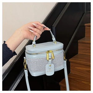 Detail of light blue box bag showing woven texture and smooth leather with gold zipper