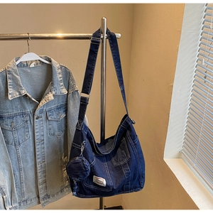 Detail shot of large dark blue denim hobo bag with adjustable strap and small coin purse