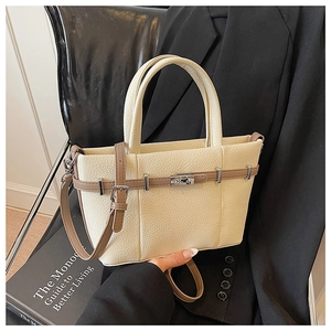 Dettaglio della borsa tote in pelle martellata con chiusura a scatto argento su sfondo in pelle