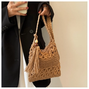 Détail d'un sac en paille tressée avec motifs floraux ajourés et accents de longues franges