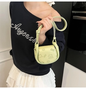Detail of light green crossbody saddle bag with cute cartoon prints and lettering