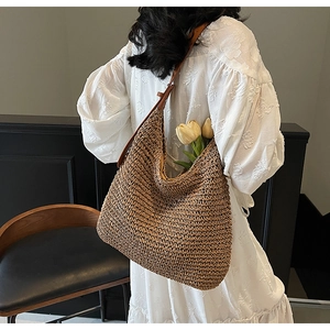 Detail of handwoven straw tote with leather strap on model wearing a white dress