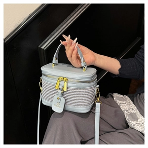 Detail of light blue box-shaped handbag with woven front panel and gold hardware