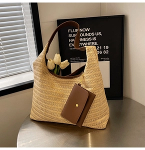 Close-up of natural woven straw tote bag with brown leather handles and small pouch